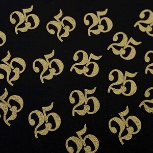 May include: A black background with multiple gold glitter-covered paper cutouts of the number 25.