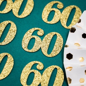 May include: Gold glitter number 60 confetti on a teal background. The number 60 is repeated multiple times.