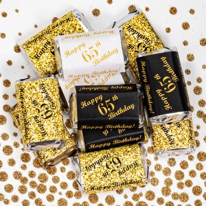 May include: Gold glitter wrapped chocolate bars with black and white labels that say "Happy 65th Birthday!"