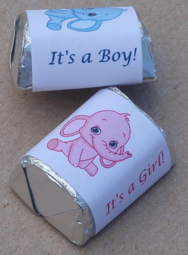 May include: Two silver foil-wrapped chocolate candies with printed labels. One label features a blue elephant with the text "It's a Boy!" and the other label features a pink elephant with the text "It's a Girl!"