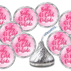 May include: Pink and white round stickers with the text "Baby it's Cold Outside" in pink. The stickers are designed to be placed on Hershey's Kisses chocolate.