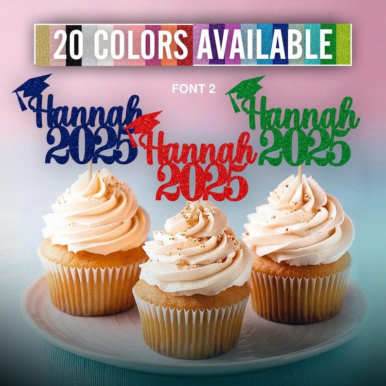 May include: Three cupcakes with graduation themed toppers. The toppers are glittery and say "Hannah 2023" in different colors. The cupcakes are frosted with white frosting and have a light brown cupcake liner.