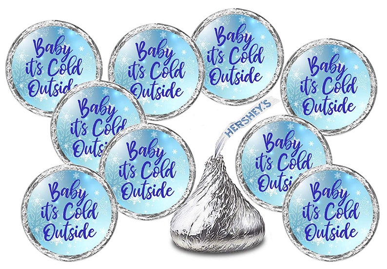 May include: A set of 10 blue and silver round stickers with the text "Baby it's Cold Outside" printed in purple. The stickers are designed to be placed on Hershey's Kisses chocolate candies.