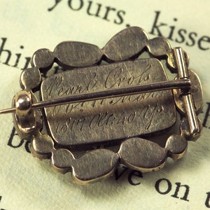 May include: A silver brooch with a decorative design and a pin on the back. The back of the brooch is engraved with the text "Pearn & Co.  Jewellers  1877 Old 40 Yps."