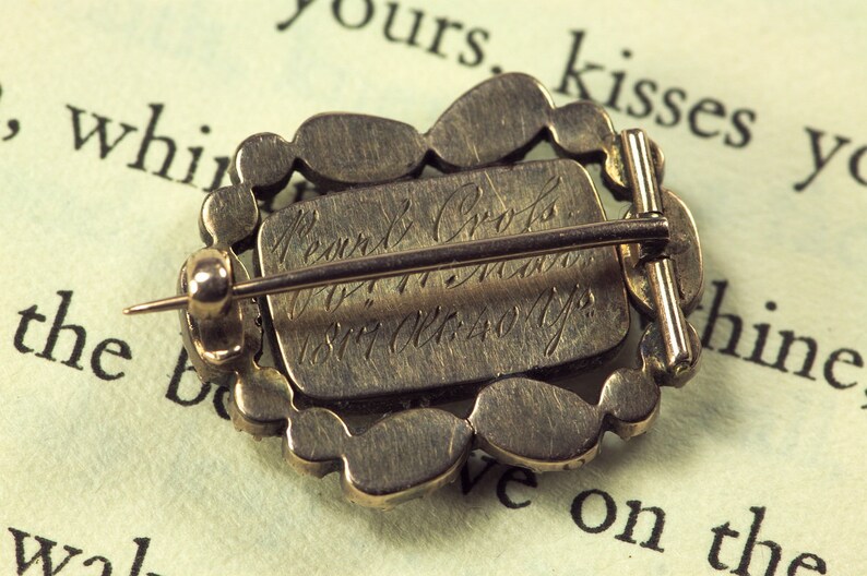 May include: A silver brooch with a decorative design and a pin on the back. The back of the brooch is engraved with the text "Pearn & Co.  Jewellers  1877 Old 40 Yps."