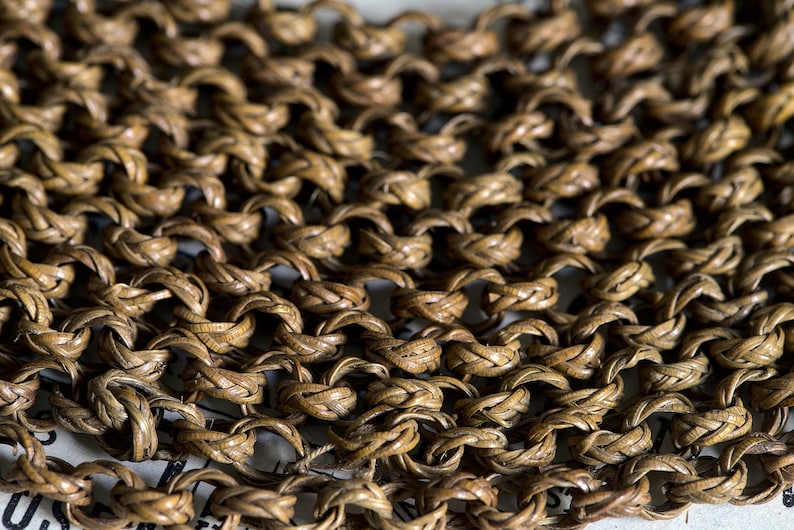 May include: Close-up of a woven chainmail made of brown leather. The chainmail is made of small, interlocked rings.