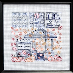以下が含まれることがあります： 星形の中空という文字が書かれた青い白のガゼボが、落ちる葉に囲まれているクロスステッチパターン。パターンには、本棚、コーヒーポット、コーヒーカップも含まれています。