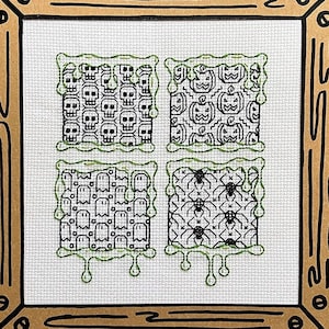 May include: A framed cross-stitch design featuring four different Halloween-themed patterns. The patterns include skulls, pumpkins, ghosts, and spiders. The frame is made of brown cardboard with a black outline.
