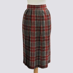 May include: A red and gray plaid pleated skirt. The skirt is knee-length and has a fitted waist.
