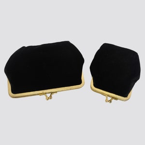 May include: Two black velvet coin purses with gold metal frames. The larger purse is on the left and the smaller purse is on the right.