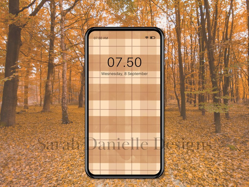 May include: A smartphone displaying a digital clock with the time 07:50 AM and the date Wednesday, 8 September. The phone's background is a brown and white checkered pattern. The phone is sitting on a bed of fallen autumn leaves.