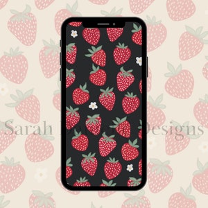 May include: A black phone screen with a pattern of red strawberries and white flowers on a black background. The phone is surrounded by a pattern of pink strawberries on a cream background.