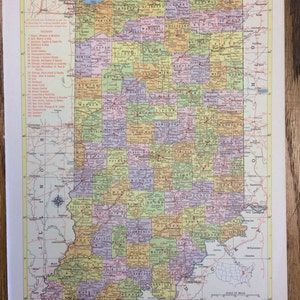May include: A vintage map of Indiana, USA, with county borders outlined in different colors. The map includes a scale of miles, state capital, and county seats. The map is printed on a cream-colored paper with a yellow border.
