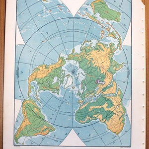 May include: A vintage world map printed on paper with a blue background and green and yellow landmasses. The map is centered on the North Pole and shows the continents in a circular arrangement. The map is titled "The World" and includes a compass rose and a scale bar.