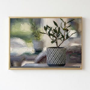 May include: An oil painting in a gold frame depicting a small olive tree in a grey patterned pot. The artwork features thick, visible brushstrokes and a soft, impressionistic style with muted green, white, and grey tones throughout the scene.