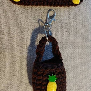 May include: Brown crocheted hand sanitiser holder with a pineapple charm and a silver keyring.