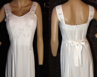 May include: A white maxi dress with a lace bodice and a tie at the back. The dress has a scoop neck and thin straps.