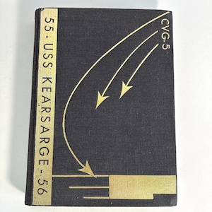 May include: A black book with gold lettering and design. The text on the spine reads "55 - USS KEARSARGE - 56". The cover features curved lines with arrows and the text "CVG-5".