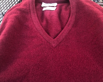 Könnte beinhalten: Ein tiefroter V-Ausschnitt-Pullover mit langen Ärmeln und einem gerippten Halsausschnitt. Am inneren Kragen befinden sich zwei weiße Etiketten mit dem Text Northcrown und weiteren Informationen, die in schwarzer Schrift aufgedruckt sind.