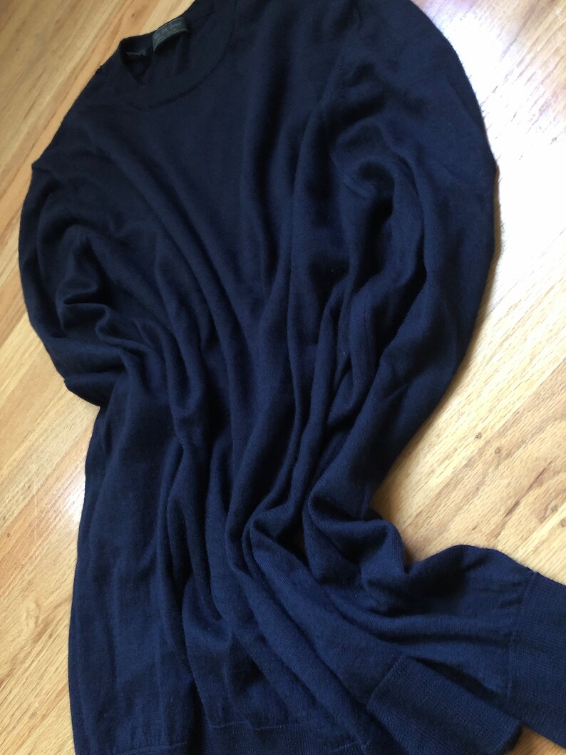 K&ouml;nnte beinhalten: Ein dunkelblauer Langarm-Pullover aus weichem, gestricktem Stoff.