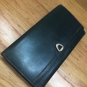 May include: A dark green leather wallet with a silver clasp.