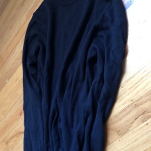 K&ouml;nnte beinhalten: Ein dunkelblauer Langarm-Pullover mit Rundhalsausschnitt.