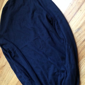 K&ouml;nnte beinhalten: Ein dunkelblauer Langarm-Pullover aus weichem, gestricktem Stoff.