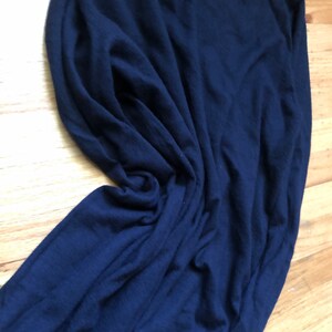 K&ouml;nnte beinhalten: Ein dunkelblauer Langarm-Pullover aus weichem, gestricktem Stoff. Der Pullover ist gefaltet und liegt flach auf einer Holzoberfl&auml;che.