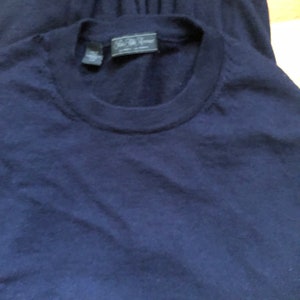 K&ouml;nnte beinhalten: Ein marineblauer Pullover mit einem kleinen, dunklen Etikett mit der Aufschrift "J.Crew" auf der Vorderseite.