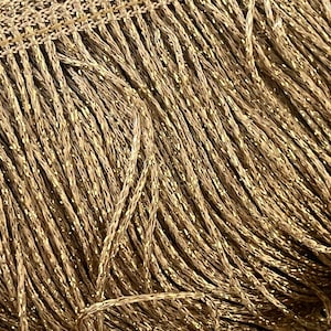 Op de afbeelding: Gouden metallic franje trim met een subtiele glans. De franje is gemaakt van dunne, gedraaide draden.