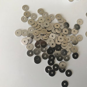 Peut inclure: Un grand tas de rondelles en métal argenté. Les rondelles sont rondes avec un trou au centre.