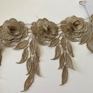 Puede incluir: Borde de encaje dorado con un diseño floral que presenta hojas y flores delicadas.