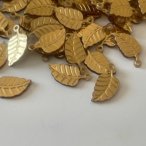 Peut inclure: Un tas de breloques en feuille d'or en forme de feuilles avec une petite boucle en haut pour accrocher.