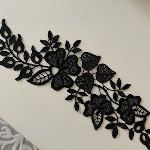 Peut inclure: Garniture en dentelle noire avec un motif floral composé de feuilles et de fleurs.