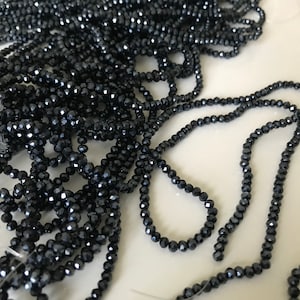 May include: A strand of black faceted beads. The beads are small and have a shiny finish.