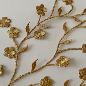 Peut inclure: Garniture florale brodée dorée avec des feuilles délicates et de petits motifs floraux. Cette garniture est parfaite pour ajouter une touche d'élégance aux vêtements, à la décoration intérieure ou aux projets d'artisanat.
