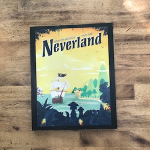 May include: A vintage-style poster with a yellow, orange, and blue colour scheme. The poster features a cartoon pirate ship sailing towards a tropical island with lush green foliage. The text on the poster reads "Where the adventure never ends, Neverland".