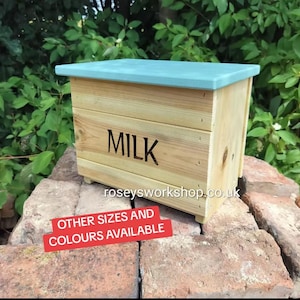 May include: A rectangular wooden crate with a light blue lid and natural wood grain sides. The word MILK is printed in black on the front. The text roseysworkshop.co.uk is visible below the word MILK, and a red sign states OTHER SIZES AND COLOURS AVAILABLE.