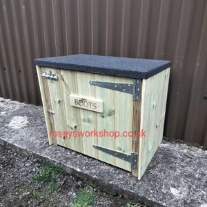 May include: A wooden boot storage box with a black rubber top. The door has a metal hinge and a sign that says "BOOTS".