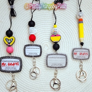 May include: Four teacher themed lanyards with black and silver glitter composition book badge holders. The lanyards feature different charms including a coffee mug, a pencil, a heart with a pencil and apple, and a heart with the words "Live Love Teach".