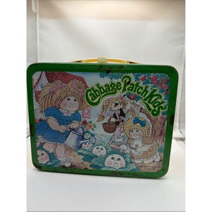 May include: Vintage green metal Cabbage Patch Kids lunchbox. The lunchbox features illustrations of Cabbage Patch Kids, a house, and the words "Cabbage Patch Kids". It has a yellow handle and a metal clasp. The lunchbox shows signs of wear.