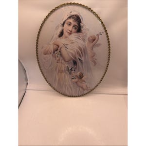 May include: Oval framed print featuring a woman in a white dress and veil, with two cherubs. The frame is a gold-colored metal with a chain-link design around the edge. The print has a vintage aesthetic.