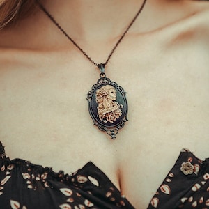 Pendentif La Catrina crâne en sucre avec roses ivoire sur noir comme collier pour tenue gothique et cosplay fantastique