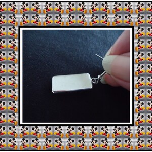 Peut inclure: Boucle d'oreille rectangulaire en argent avec une finition lisse et polie. La boucle d'oreille est pr&eacute;sent&eacute;e pendante &agrave; l'oreille d'une personne.