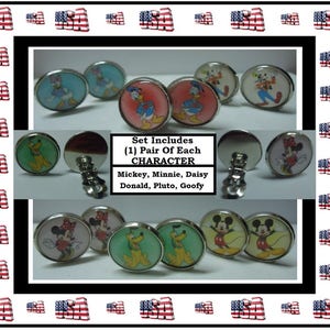 May include: A set of six pairs of clip-on earrings featuring various Disney characters, including Mickey Mouse, Minnie Mouse, Donald Duck, Daisy Duck, Pluto, and Goofy. Each pair of earrings has a different character and is presented on a white background. The text "Set Includes (1) Pair Of Each CHARACTER Mickey, Minnie, Daisy Donald, Pluto, Goofy" is displayed below the earrings.