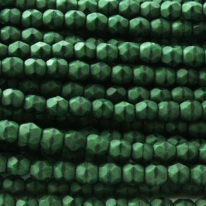 Puede incluir: Una hebra de cuentas de vidrio verde oscuro con forma hexagonal facetada.