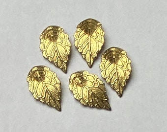 May include: Five gold-colored metal leaf charms with a detailed design. The leaves are all the same size and shape, and they have a slightly textured surface.