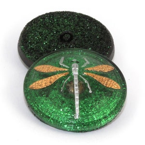 May include: Green glitter button with a silver dragonfly with gold wings. The button has a black back.