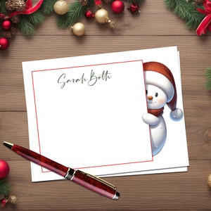 May include: A white card with a red border and the name "Sarah Beth" written in cursive. A snowman with a red hat and scarf is peeking out from the right side of the card.