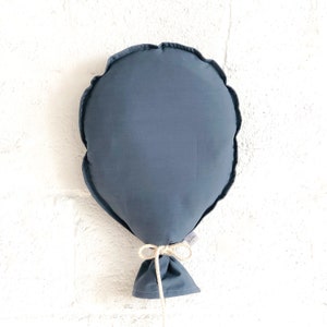 May include: A dark blue balloon cushion with a white string tied around the bottom. The cushion has a white tag with the word "Little" on it.